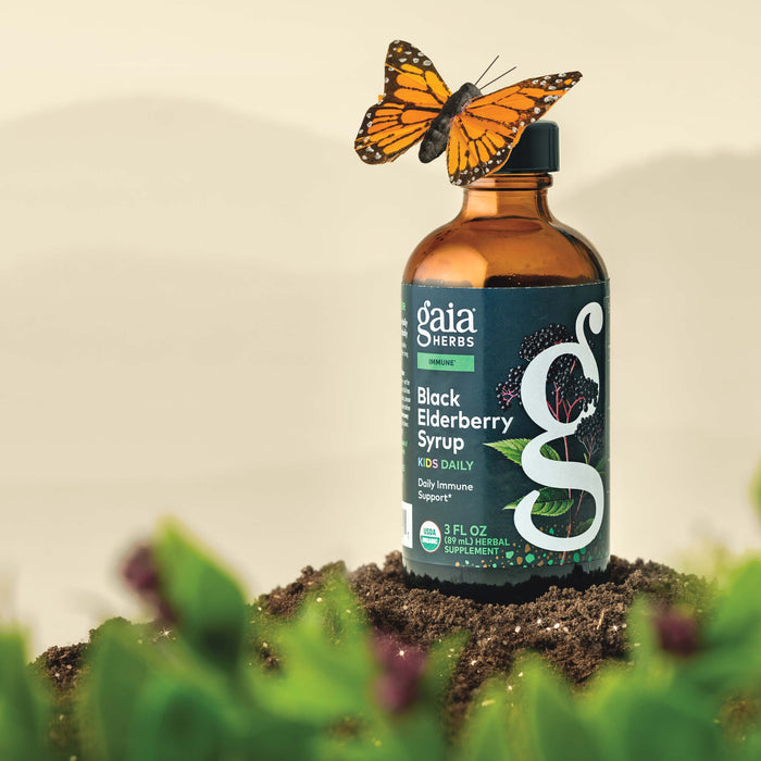 Gaia Herbs Black Elderberry Syrup Kids Daily 3 ounce bottle with a butterfly on top, surrounded by greenery.