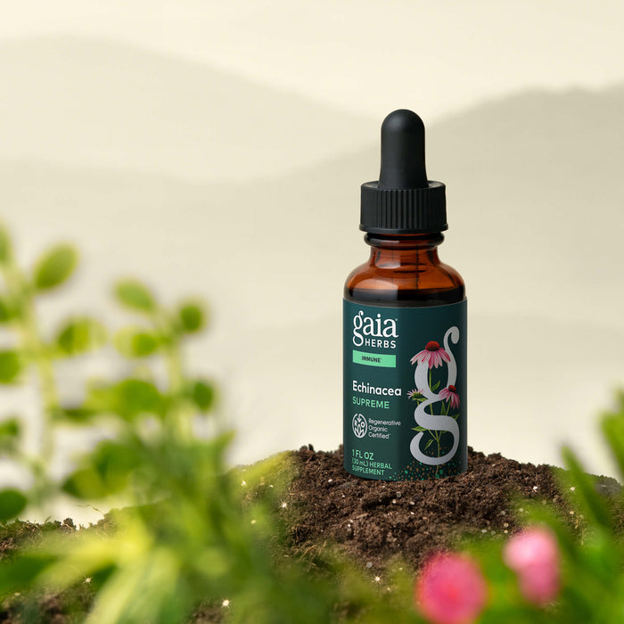 Gaia Herbs Echinacea Supreme tincture bottle on a natural background with plants and flowers.