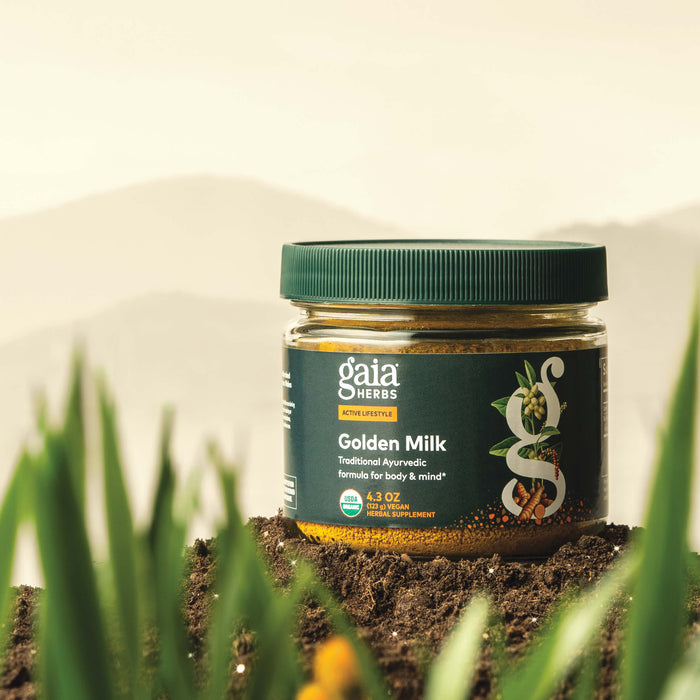 Gaia Herbs Golden Milk 4.3 ounce powder supplement in a bottle with grass and soil in the foreground