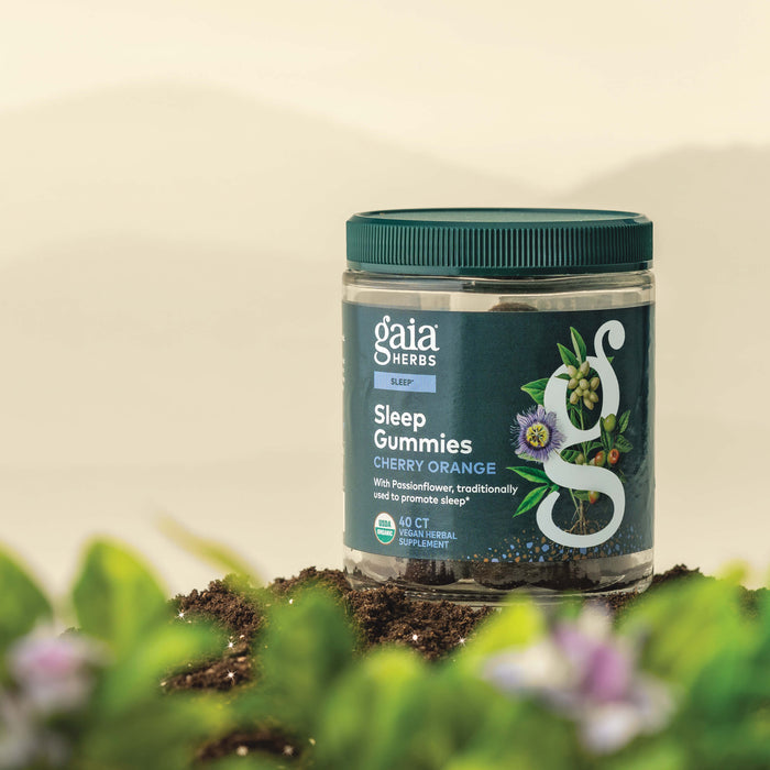 Gaia Herbs Sleep Gummies 40 count bottle on a natural background with plants and flowers.