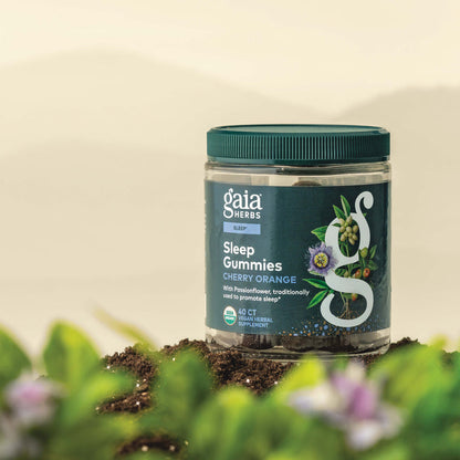 Gaia Herbs Sleep Gummies 40 count bottle on a natural background with plants and flowers.